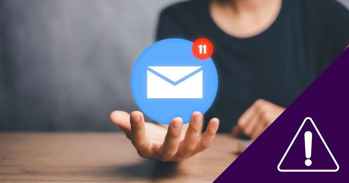 Hand holding a blue email notification icon with a warning symbol, symbolizing urgent meeting follow-up tasks.